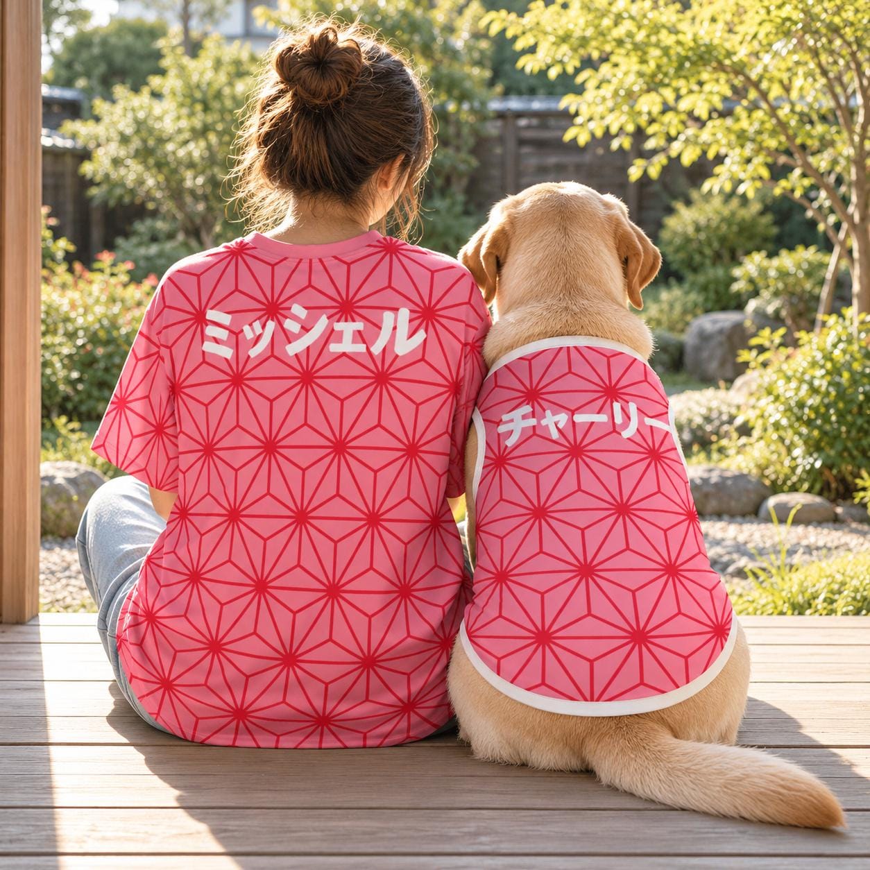 Matching dog and owner shirts seen from behind: a person and a Labrador sit side by side on a wooden porch in the pink asanoha hemp leaf design, with the names Michelle and Charlie in Japanese katakana.